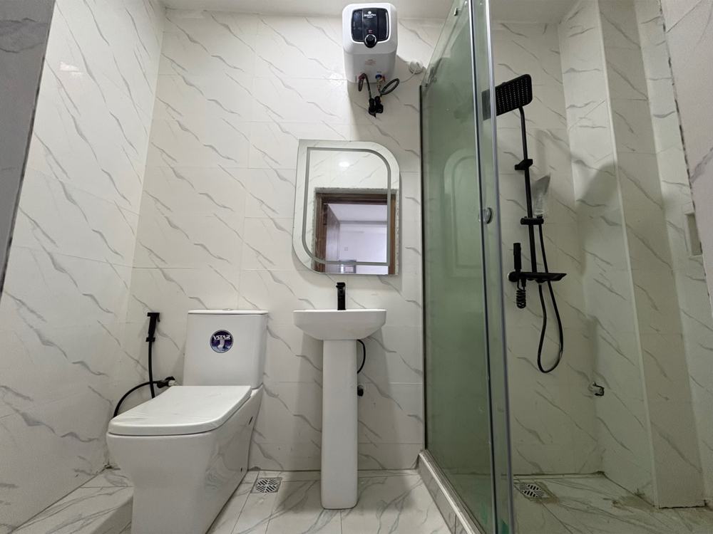 Bathroom with glass shower, pedestal sink and marble tiles