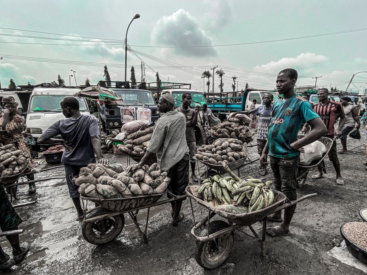 Traders with wheelbarrows of yams and plantain at a Lagos market